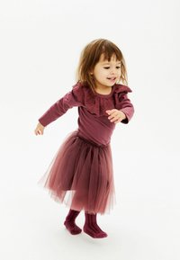 Mauve dolgimi rokavi majica z nabranim čipkastim ovratnikom, v kombinaciji z večplastno tila krilo v temnejšem mauve odtenku, nogavice do gležnjev z rebrasto teksturo.