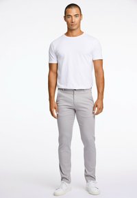 Herroutfit som består av en kroppsnära vit T-shirt i bomull och ljusgrå raka byxor. Matchat med vita sneakers. Enkel design, utan mönster.