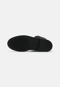 Suela de zapato negra con agarre texturizado en la parte delantera, tacón liso, tamaño 37, y marca "Tommy Hilfiger" en la suela media.