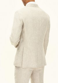 Ljusbeige linnekavaj med skräddarsydd design, subtil textur, med notchade slag och en enda slits bak.