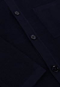 Donkerblauwe cardigan met geribbelde textuur, voorzien van zwarte knopen, een borstzak en een klassieke knoopsluiting.