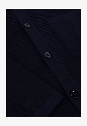 Donkerblauwe cardigan met geribbelde textuur, voorzien van zwarte knopen, een borstzak en een klassieke knoopsluiting.