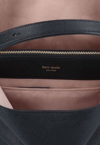 Fekete bőr kézitáska texturált külsővel, arany cipzárral és világos rózsaszín belső béléssel. Az arany "Kate Spade" logóval rendelkezik.