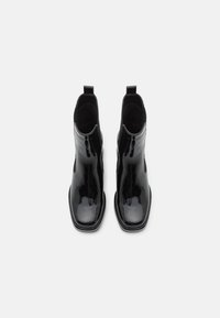 Botas de tobillo de charol negro con una forma elegante, laterales altos, lengüetas traseras y una superficie lisa y brillante. Diseño de punta cuadrada.