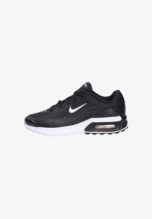 Zapatilla deportiva negra de malla con acentos blancos, que presenta una suela acolchada, punta redondeada y un detalle de amortiguación de aire visible en el costado.