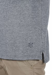 Grå, teksturert stoff kortermet skjorte. Har et lite logo ved kanten og sidesplitter i bunnen for lettere bevegelse.