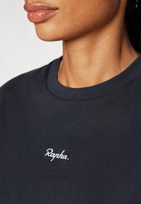 Navyblaues Baumwoll-T-Shirt mit rundem Halsausschnitt und weißem gesticktem Logo "Rapha." auf der Brust. Glatte Textur.