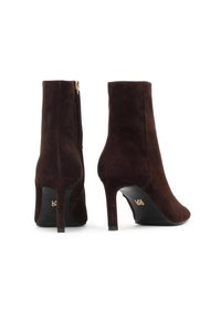 Hnědé nubukové kotníkové boty s elegantním designem, špičatou špičkou a vysokým podpatkem. Boční zip a jemný zlatý kovový detail na podpatku.
