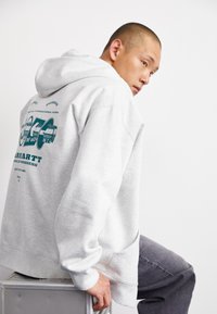Gray cotton hoodie with a large graphic print on the back, featuring teal accents. It has a relaxed fit and kangaroo pocket.