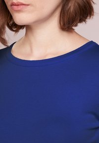 Camiseta ajustada de color azul real, con cuello redondo y mangas cortas; tejido suave y elástico; detalles de costura mínimos.