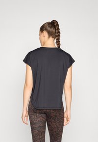 Svart kortärmad topp med rund halsringning, lättviktigt tyg, lös passform och rundad fåll, kombinerad med bruna leggings med leopardmönster.