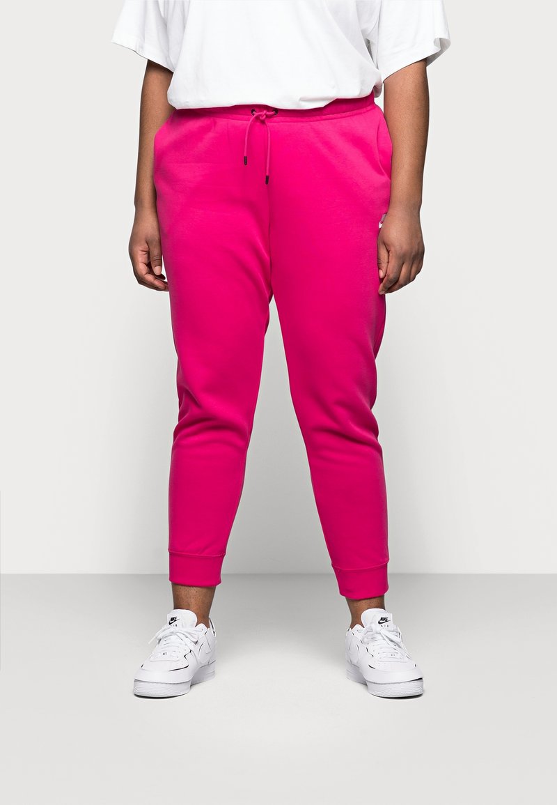 Fuchsiové joggingové kalhoty s elastickým pasem, zúženými nohavicemi a žebrovanými manžetami. Stylizované s volným bílým tričkem a bílými teniskami.