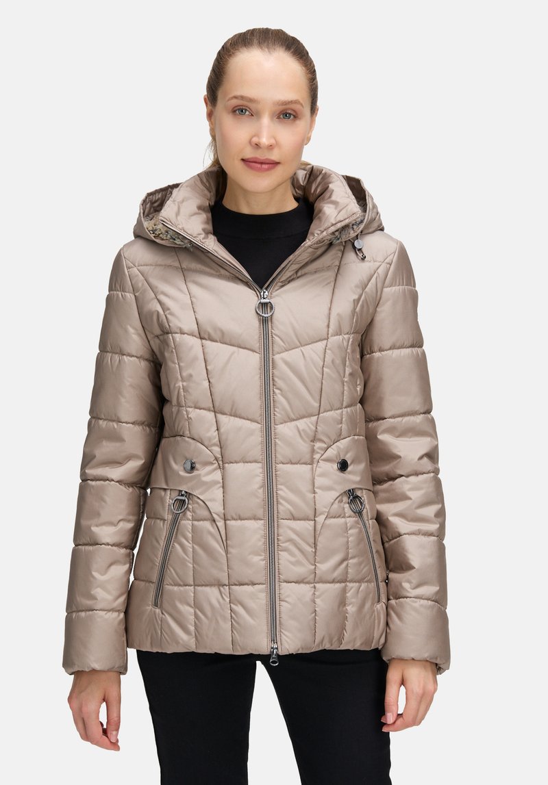 Jasno beżowa pikowana kurtka z kapturem, wyposażona w kieszenie na zamek, zapięcia na zatrzaski oraz błyszczące wykończenie. Teksturowana tkanina z wzorem panelowym.