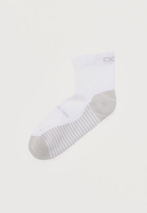 Calzino alla caviglia bianco con punta e tallone grigi, strisce grigie sulla suola e un logo parziale del marchio vicino al bordo.