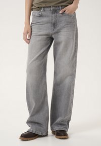 Jeans a gamba larga grigio chiaro in denim con una consistenza liscia, dotati di chiusura a bottone e zip, e tasche frontali.