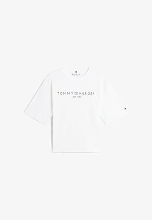 Camiseta blanca de algodón con mangas cortas y anchas, con un logo frontal: "TOMMY HILFIGER EST. 1985" en azul oscuro. Diseño simple y clásico.