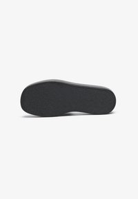 Black shoe sole with a textured surface, featuring a rounded shape and a slight upward curve at the heel; no visible logos or patterns.