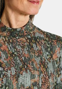 Langarmshirt met een hoge kraag, voorzien van een gestructureerd, meerkleurig patroon in groen, oranje en zwart.