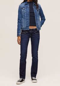 Jeansjacka med klassisk skärning, ljusblå tvätt och knappstängning. Mörkblå jeans med slim fit och subtila sömdetaljer. Svarta sneakers.