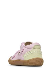 Light pink leather shoe with a green suede accent, velcro strap closure, and textured rubber sole. Rounded shape with stitched details.