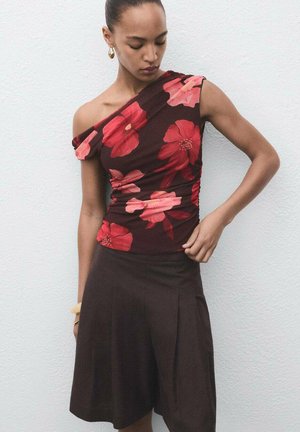 Floral print brown top with one shoulder design, featuring large red and pink flowers. Paired with a dark brown pleated skirt.