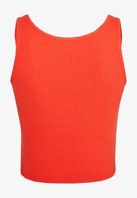 Débardeur rouge à côtes avec un col arrondi et sans manches. Le tissu est doux et ajusté, offrant une silhouette proche du corps et confortable.