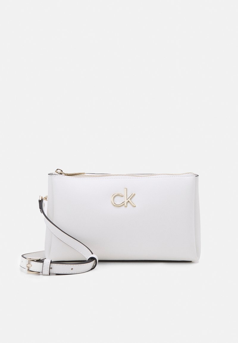 White leather crossbody bag with a gold CK logo, zip closure, and additional detachable black strap. Smooth texture and minimalist design.