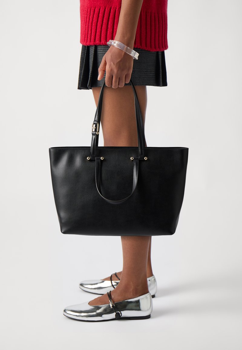 Borsa tote in pelle nera con due manici, dettagli in oro e un design strutturato. Presenta una superficie liscia e un ampio interno.