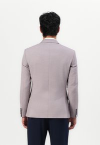 Helles graues maßgeschneidertes Blazer, einreihiges Design, mit Reverskragen, subtile Textur, mit schwarzen Knopfakzenten, von hinten präsentiert.