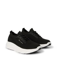 Un paio di sneakers nere in maglia con suole chunky bianche e logo Champion sul lato, su uno sfondo bianco.
