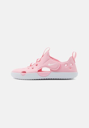 Zapato de agua rosa Nike con suela blanca, agujeros de ventilación, correa ajustable y lengüetas para tirar en talón y lengüeta.