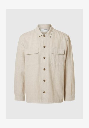 Gaismi kautrīgi pelēks lina krekls ar garām piedurknēm, priekšējā pogu aizdare, divas krūšu kabatas un brūnas pogas. Gluda tekstūra ar ikdienišķu dizainu.