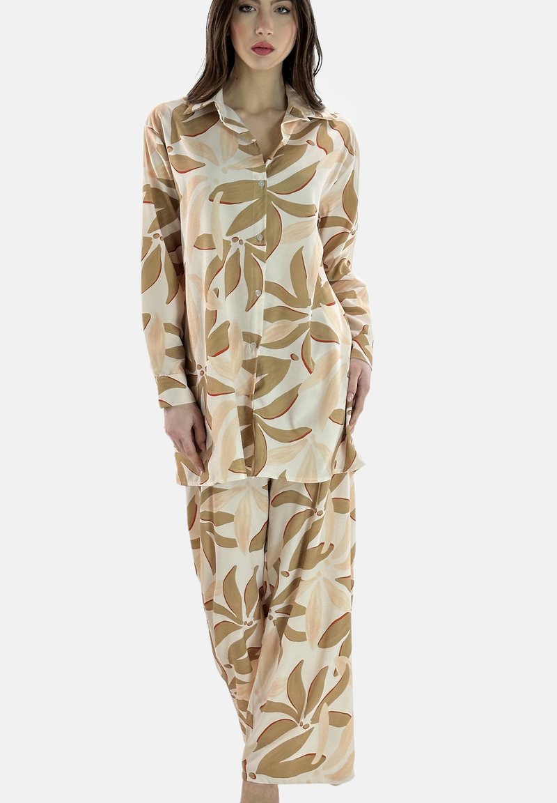 Langarm pyjama set in crème met grote bruine en roestkleurige bladvormen. Zachte stof met een ontspannen pasvorm. Broek met elastische tailleband.