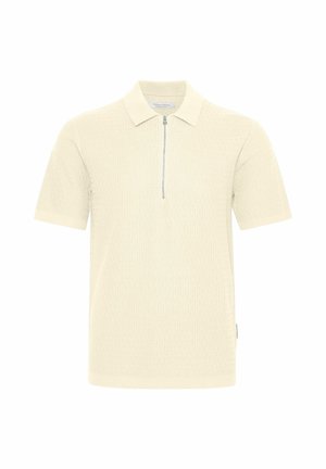 Polo à manches courtes en crème clair, présentant un motif en tricot texturé, une fermeture à demi-zip et un col classique. Design simple et moderne.
