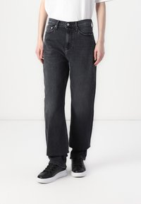 Jean large gris foncé en denim avec taille haute, doté de poches frontales, d'une fermeture à bouton et de détails de couture subtils.