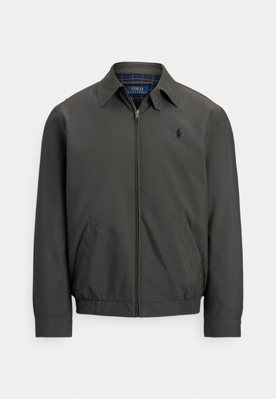 Chaqueta bomber gris oscuro hecha de tejido liso con cremallera frontal, bolsillos laterales y puños elásticos. Presenta un logo bordado en el pecho.