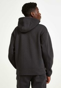 Schwarzer Kapuzenpullover mit lässiger Passform, weichem Material, gerippten Bündchen und Saum, ausgestattet mit einer Kängurutasche und minimalen Nähten.