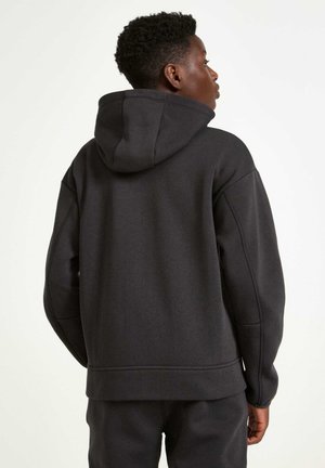 Sort hættetrøje med en afslappet pasform, blød tekstur, ribbede manchetter og kant, med en kængurulomme og minimale sømme.