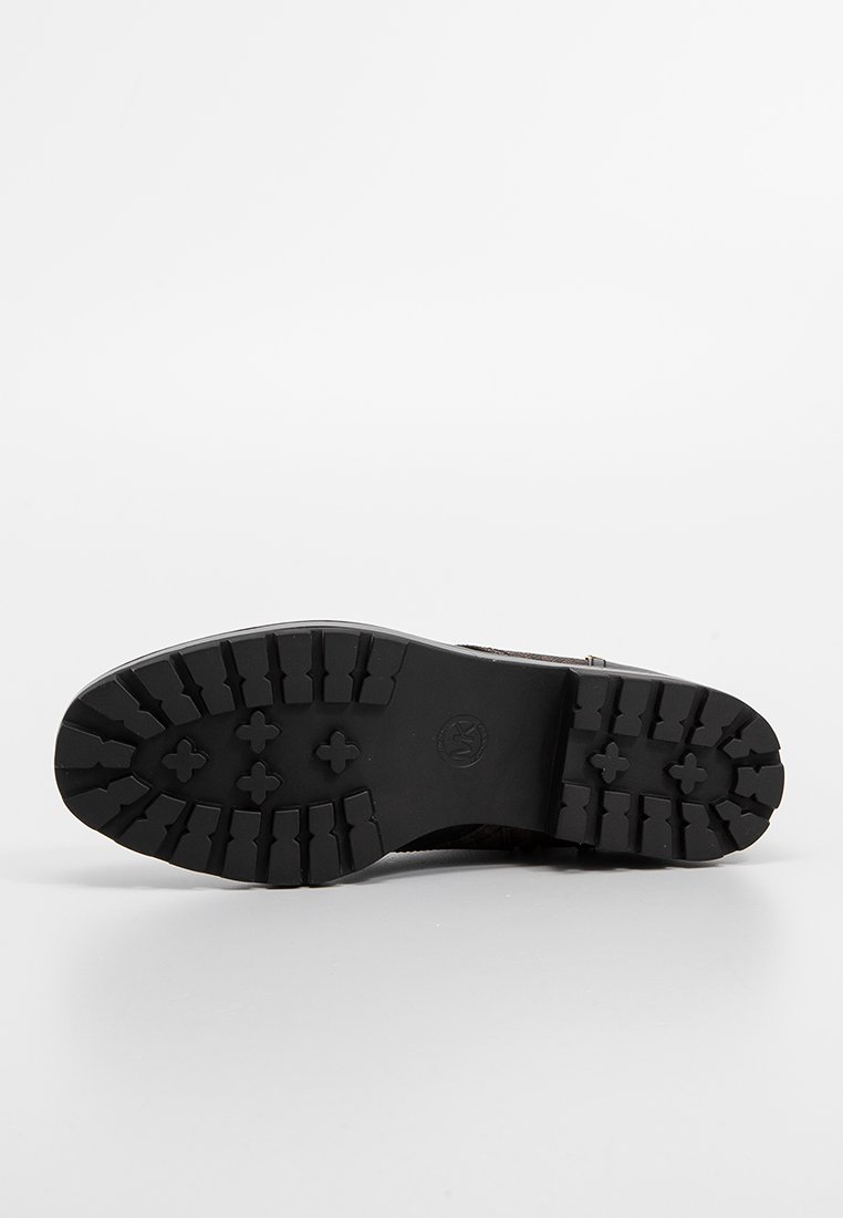 Zwarte rubberen zool met een gestructureerd profiel. Heeft een afgeronde vorm en een logo-embleem. Ontworpen voor duurzaamheid en grip.