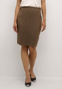 Bruine gebreide pencilrok met een gestructureerd patroon, hoge tailleband, knie-lengte, gecombineerd met zwarte puntige hakken met metalen accenten.