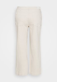 Jasnobeżowe spodnie o szerokich nogawkach z gładką fakturą, wyposażone w dwie tylne kieszenie i dyskretny detal na pasku.