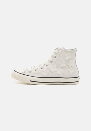 White high-top sneakers with flower-shaped accents, made of leather, featuring a lace-up design and black sole stripe. Simple and modern.