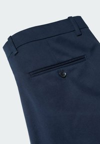 Pantalon habillé bleu foncé avec une seule poche passepoilée à l'arrière, fermée par un bouton noir et des passants de ceinture à la taille.