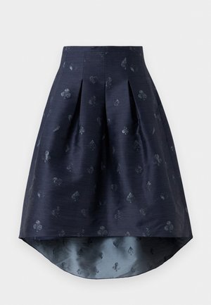 Jupe bleu marine asymétrique avec plis et motif subtil de cartes à jouer dans un tissu légèrement brillant.