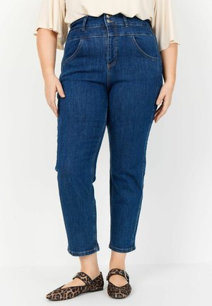 Dark blue high-waisted jeans with front pockets, tapered leg, and minimal stitching details. Paired with brown leopard print flats.