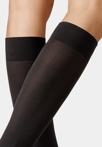 Schwarze, oberschenkellange Socken mit einer glatten, durchsichtigen Textur und einem breiten, elastischen schwarzen Bund oben. Geeignet für verschiedene Anlässe.
