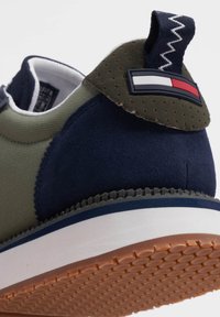 Sneaker verde e blu navy con tomaia in pelle scamosciata e mesh, suola in gomma e una toppa con il logo in rosso, bianco e blu sul tallone.