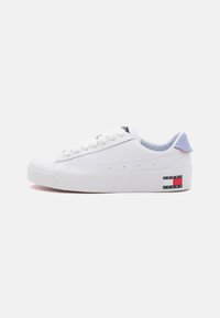 Zapatilla blanca con parte superior de cuero liso, puntera redonda, cordones blancos prominentes y un acento azul claro en el talón. Pequeño logo en el costado.