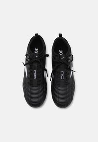 Black soccer shoes with a textured leather upper, featuring quilted patterns, black laces, and white accents on the sides and branding.