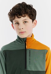 Maglione in felpa a mezza zip verde e arancione con tessuto leggero e testurizzato, pannelli a contrasto e tasca con zip e dettaglio del logo.